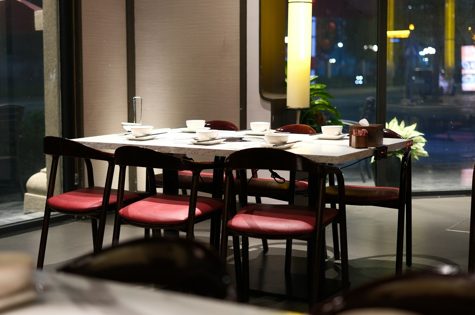 Interior of a restaurant with tables and chairs positioned near a window, highlighting Singapore's finest culinary offerings.
