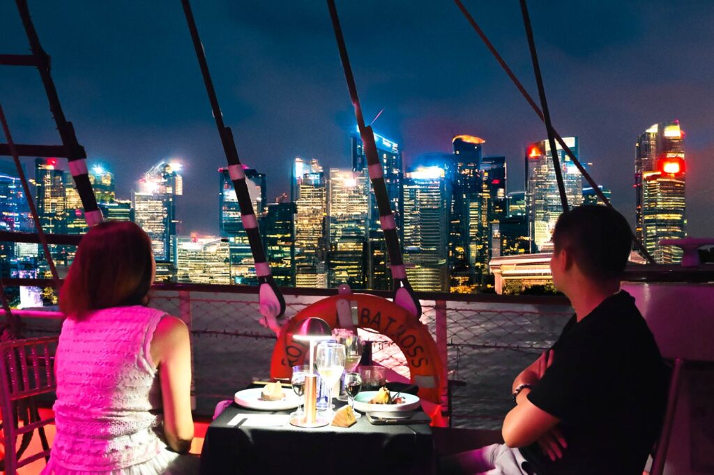 Romantic rooftop dining overlooking the Singapore skyline on a luxury ship deck.