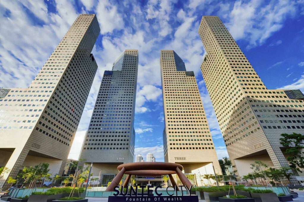 Iconic Suntec City towers with the Fountain of Wealth in the foreground under a bright blue sky.