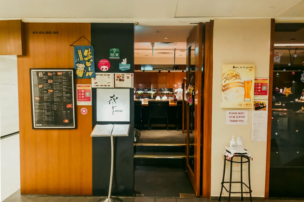 Hanashizuku Japanese Cuisine entrance at Cuppage Plaza with menu board, cozy izakaya-style interior and signage for a hidden Japanese restaurant in Singapore, shot angle: eye-level wide front view.