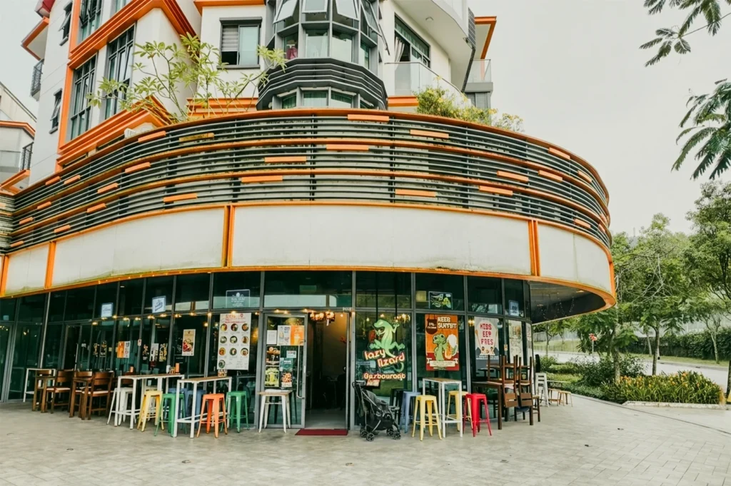 Wide-angle eye-level shot of a colorful corner restaurant exterior with curved balcony railings, glass storefront, and outdoor seating in a modern urban setting.