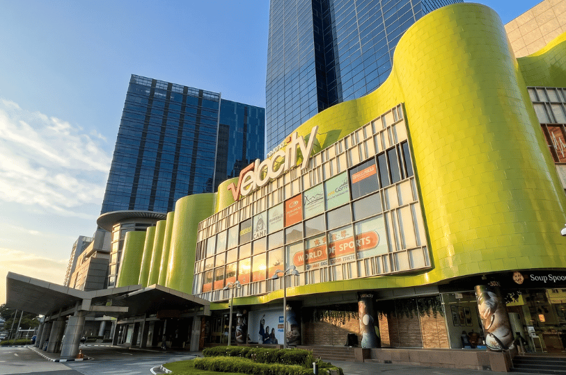 The exterior facade of the Velocity shopping mall in Singapore featuring a bright green curved wall.