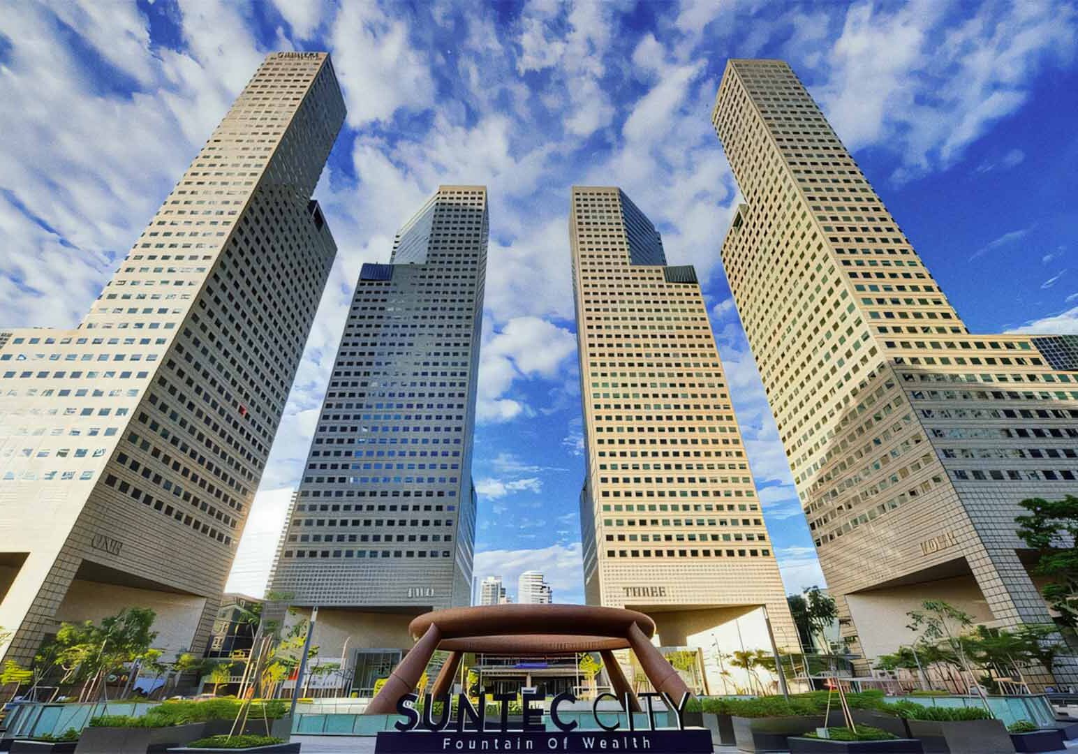 Iconic Suntec City towers with the Fountain of Wealth in the foreground under a bright blue sky.