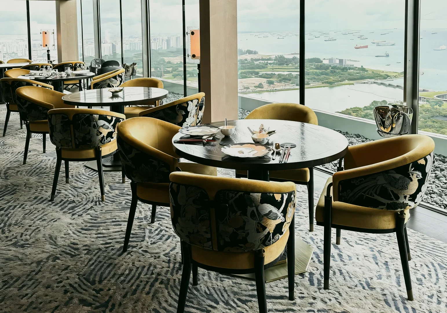 1 Jin Ting Wan Marina Bay Sands Wide‑angle interior shot of Jin Ting Wan Marina Bay Sands showing elegant round tables and Song Dynasty–inspired seating, with panoramic Marina Bay and Singapore waterfront views through floor‑to‑ceiling windows.