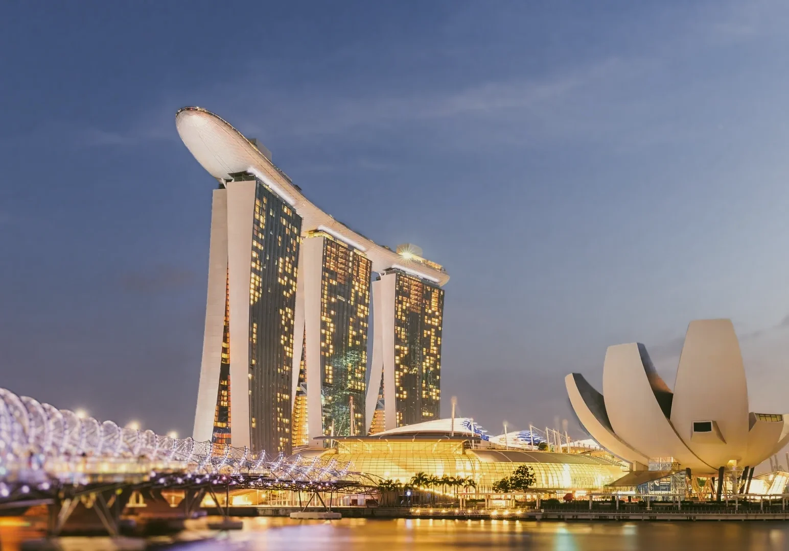 Low‑angle wide shot of Marina Bay Sands skyline at dusk, featuring luxury hotel towers and waterfront architecture in Singapore, iconic dining and travel landmark.