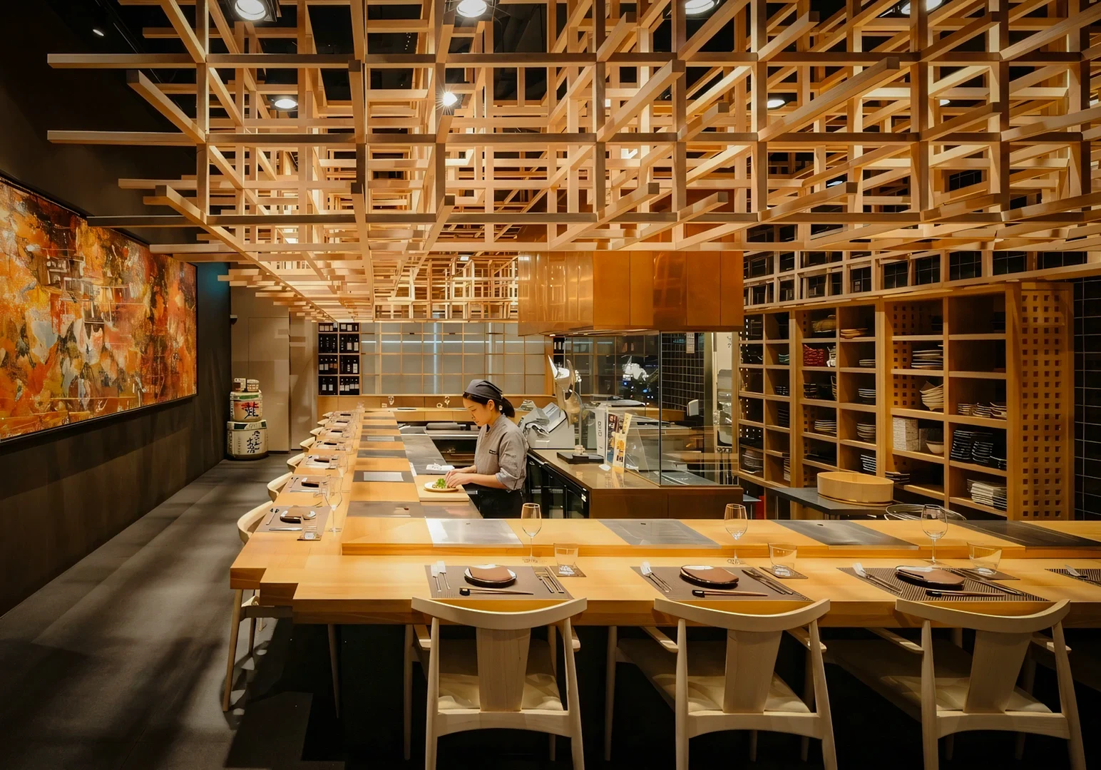 Wide-angle shot of a modern Japanese sushi bar with wooden lattice ceiling design, chef preparing dishes at counter seating in a minimalist fine dining restaurant interior.