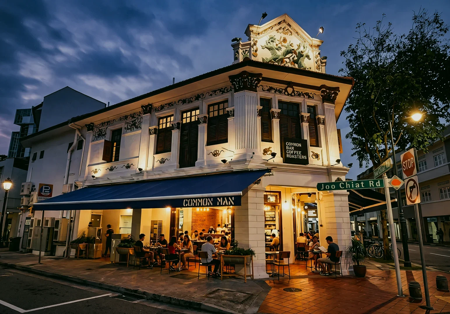1 What Makes a Restaurant Feel Timeless Rather Than Trendy Low-angle wide shot of Common Man Coffee Roasters in Joo Chiat Singapore, a heritage shophouse café with outdoor dining, warm lighting, and neighborhood atmosphere.