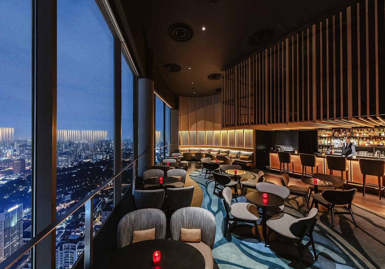 Rooftop lounge bar with panoramic city skyline views at night.