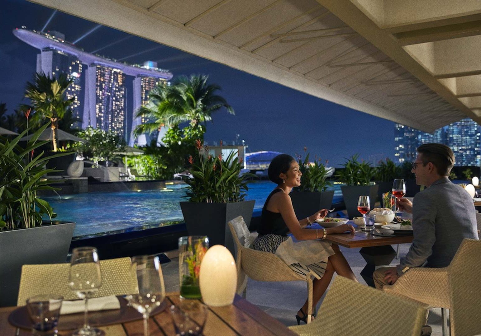 Scenic waterfront dining at night with views of Marina Bay Sands and city lights.