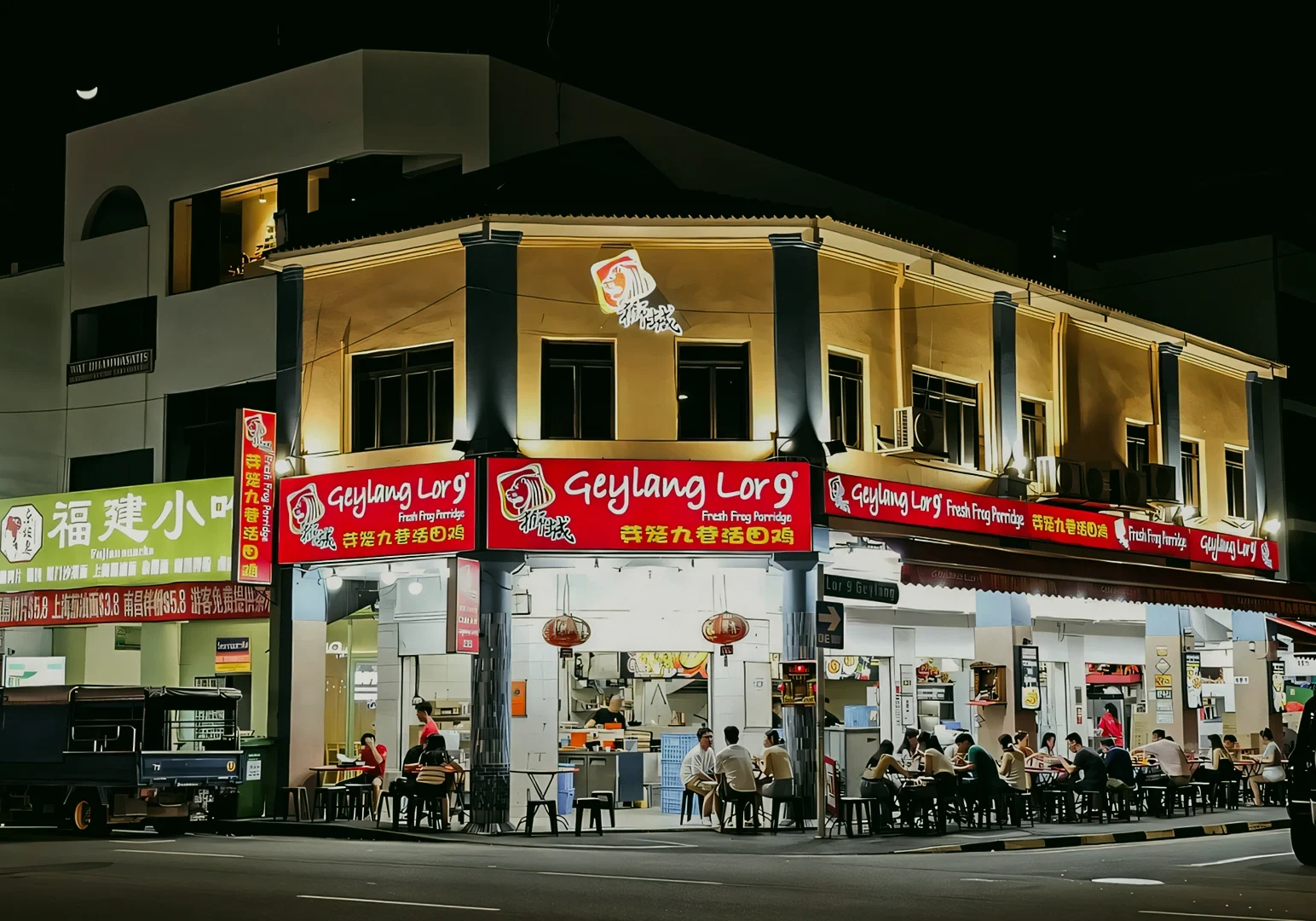 Geylang Lor 9 fresh frog porridge restaurant bustling with diners under bright signage at night, shot at a frontal mid-angle architectural view.