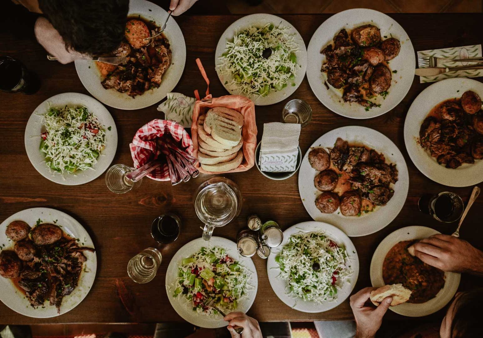Top-view spread of assorted dishes, salads, and bread on a rustic dining table.