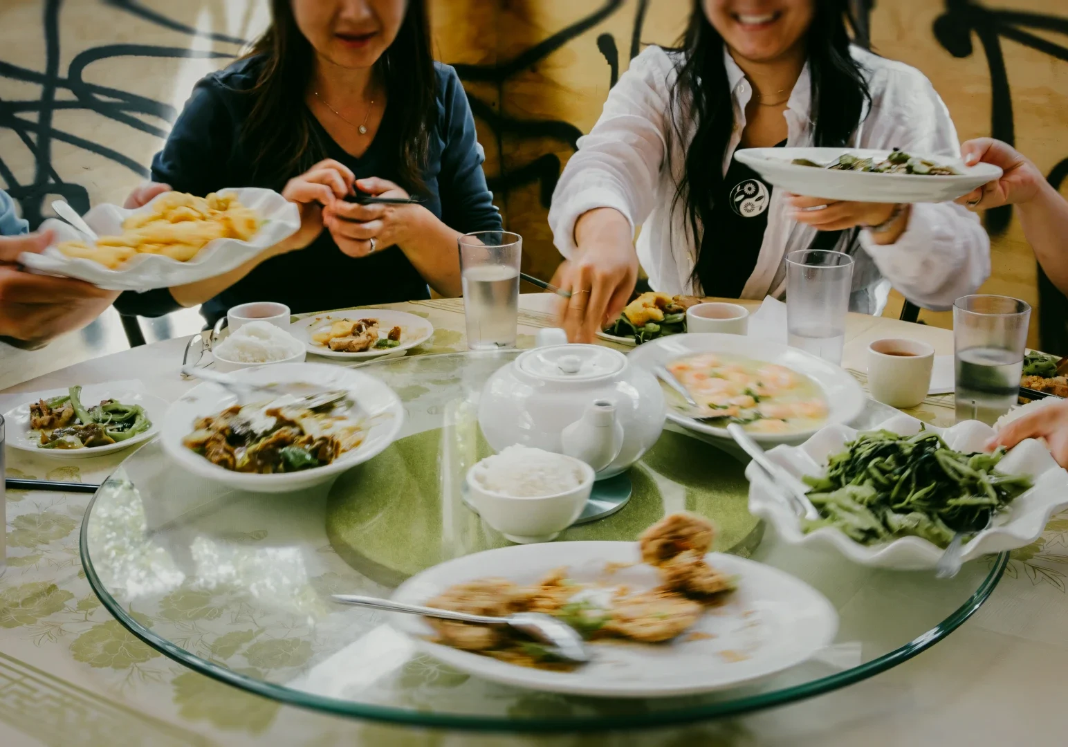 2 Restaurant Hopping Eye‑level wide shot of a shared round dining table filled with Chinese dishes, including stir‑fried vegetables, seafood, rice, and plated mains, capturing communal dining, restaurant hopping, and social food experiences.