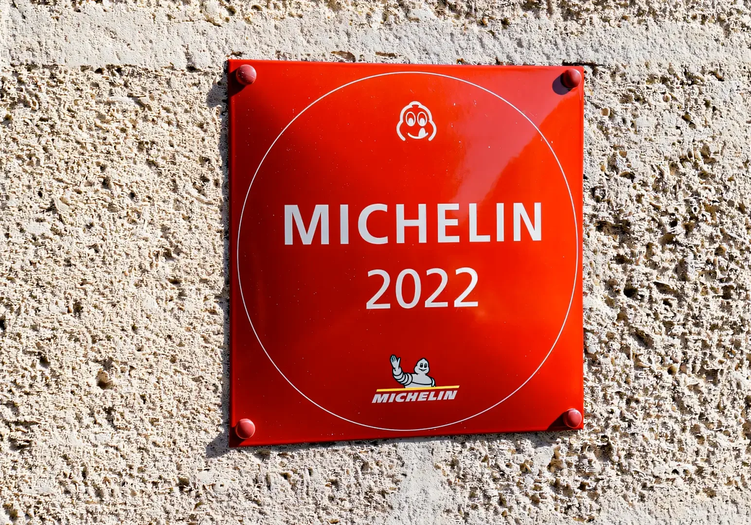 Close‑up of a red Michelin 2022 plaque mounted on a textured stone wall.