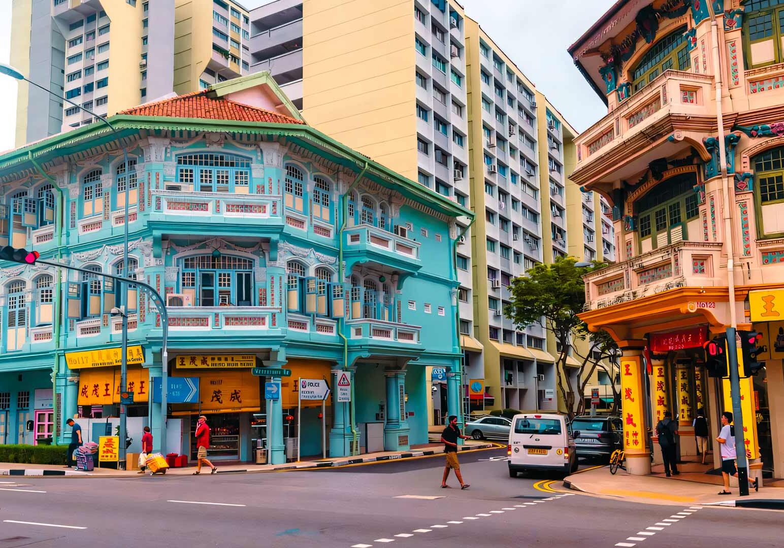 Historic pastel‑colored shophouses with intricate architectural details at a street corner, contrasting with modern high‑rise residential buildings in the background.
