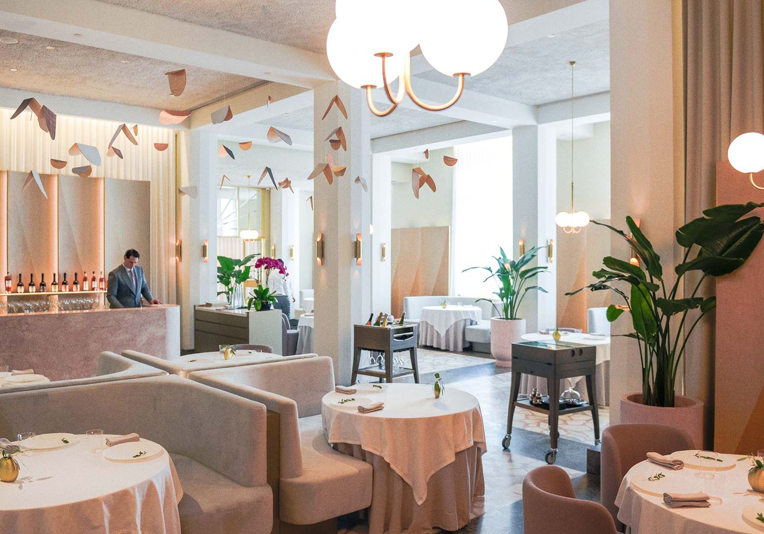Elegant Odette Singapore interior featuring soft pastel décor, sculptural ceiling art, and refined fine‑dining table settings.