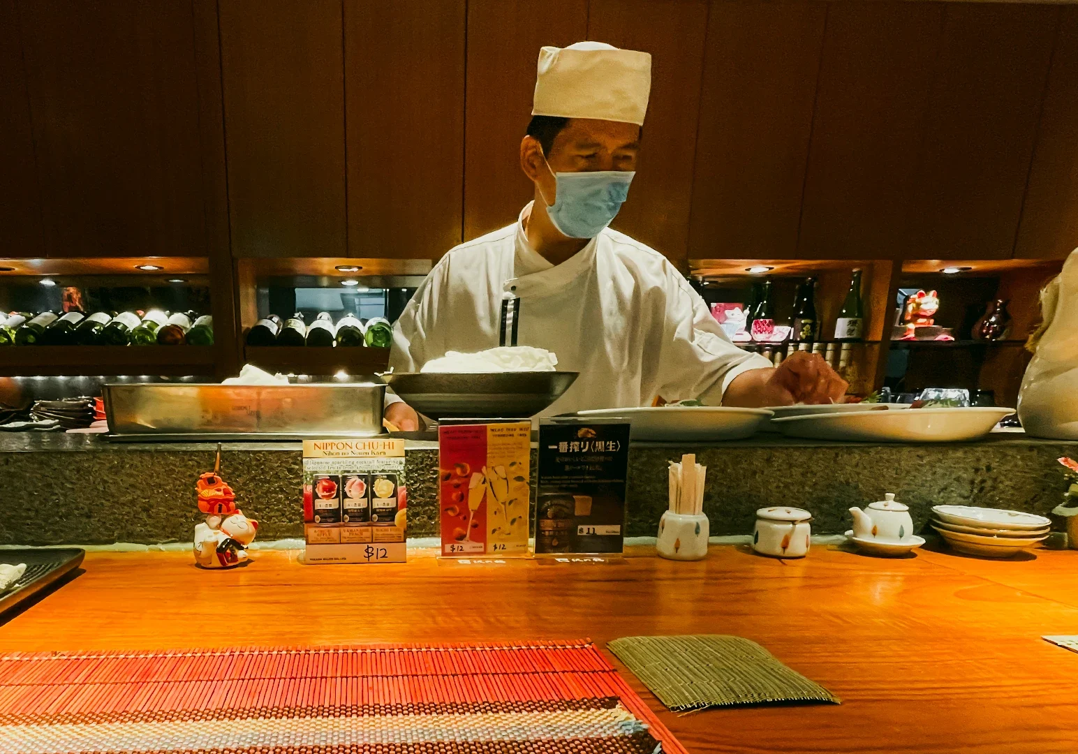 4 Hanashizuku Japanese Cuisine Eye-level medium shot of Japanese chef preparing seasonal dishes behind sushi counter at Hanashizuku Japanese Cuisine in Cuppage Plaza Singapore