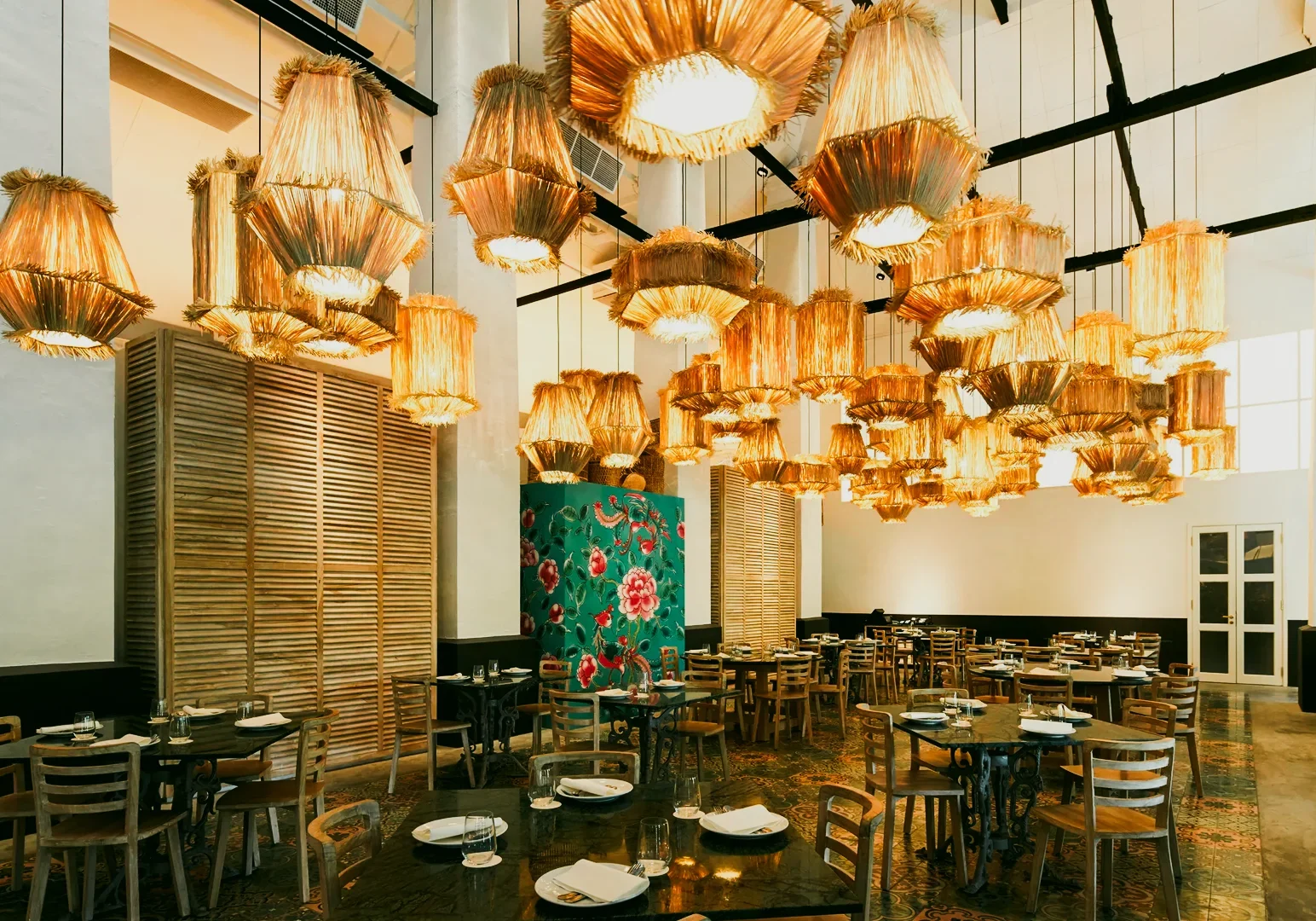 4 The Dedication Behind Peranakan Cuisine Singapore Through a Chef’s Work Wide-angle interior shot of a modern Peranakan restaurant in Singapore with woven pendant lights, wooden tables, patterned tiles, and neatly set dining space.