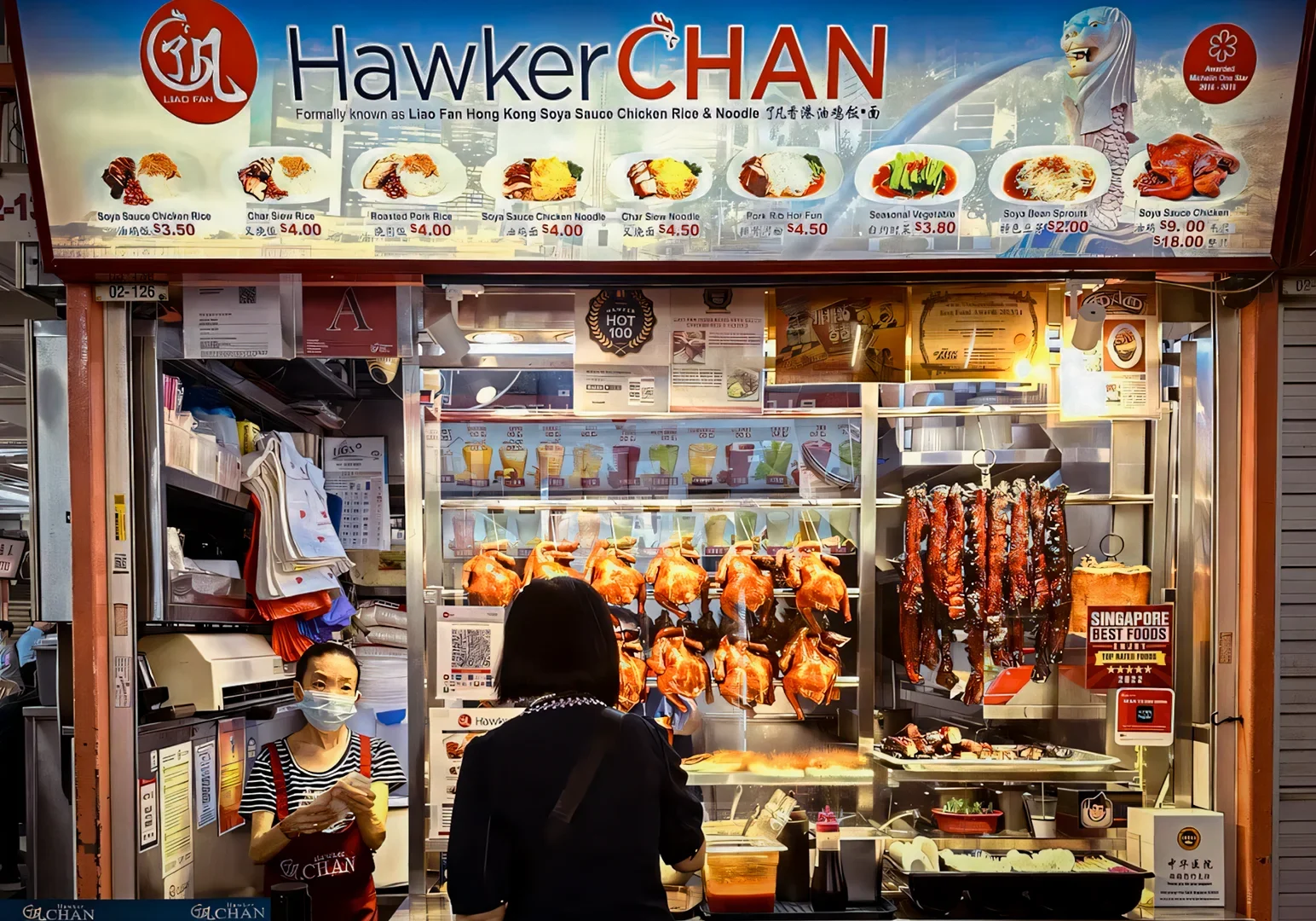 Front view of a Hawker Chan food stall displaying roasted meats, menu boards, and hanging soy‑sauce chicken in a busy hawker center.