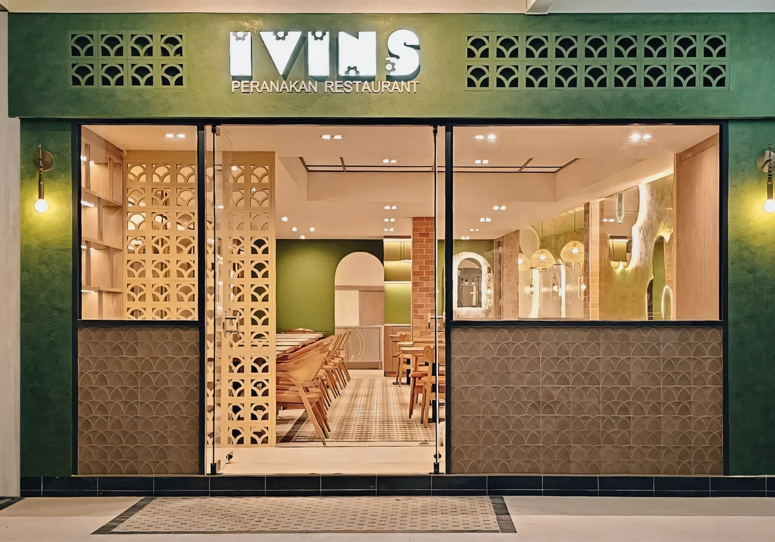IVINS Peranakan Restaurant entrance with green-and-cream modern design, patterned walls, wood accents, and warmly lit interior dining space.
