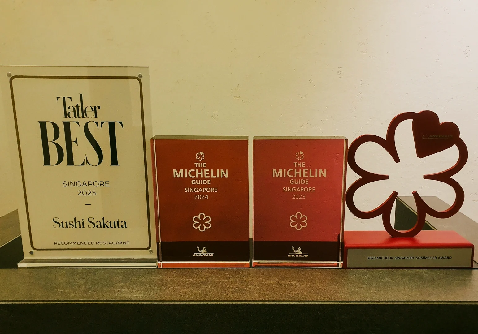 Eye-level frontal shot of Michelin Guide and dining awards displayed on a shelf, highlighting Michelin recognition alongside restaurant accolades.