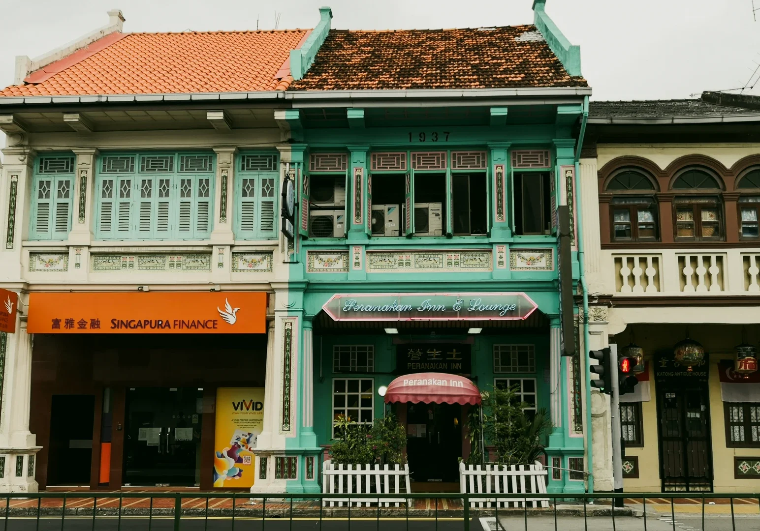 5 The Dedication Behind Peranakan Cuisine Singapore Through a Chef’s Work Eye-level street view of colorful Peranakan shophouses in Singapore with pastel facades, decorative tiles, shuttered windows, and the ‘Peranakan Inn & Lounge’ storefront.