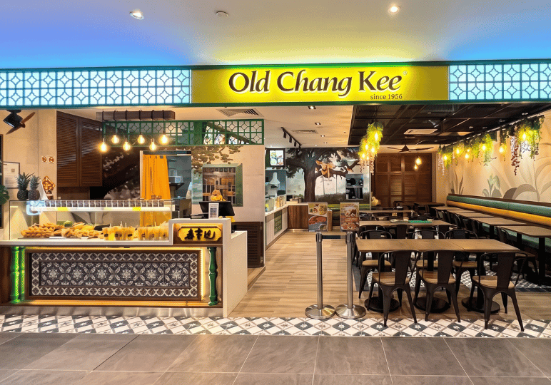 5-curry-times-velocity The storefront of an Old Chang Kee restaurant in Singapore, highlighting its bright yellow signage and modern interior seating.