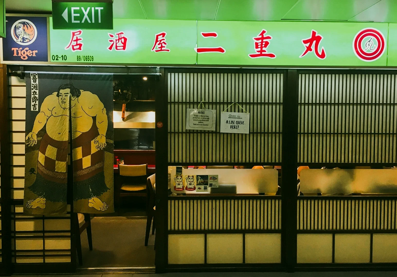 6 Cuppage Plaza Food Frontal eye-level shot of Izakaya Nijumaru entrance with Japanese noren curtain and sumo artwork, representing authentic izakaya dining experience in Cuppage Plaza Singapore