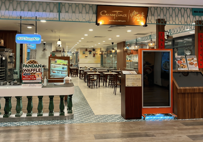 6-curry-times-velocity The entrance to a Curry Times restaurant, showing an open dining area with traditional decor and wood-paneled walls.