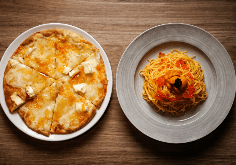 7-orchard-plaza-stalls A gourmet fusion meal displaying a sliced multi-cheese pizza next to a plate of spaghetti generously topped with fresh sea urchin (uni) and salmon roe (ikura).