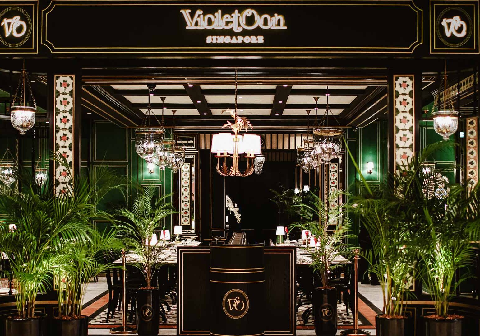Violet Oon Singapore restaurant entrance with lush greenery and classic black‑and‑gold design.