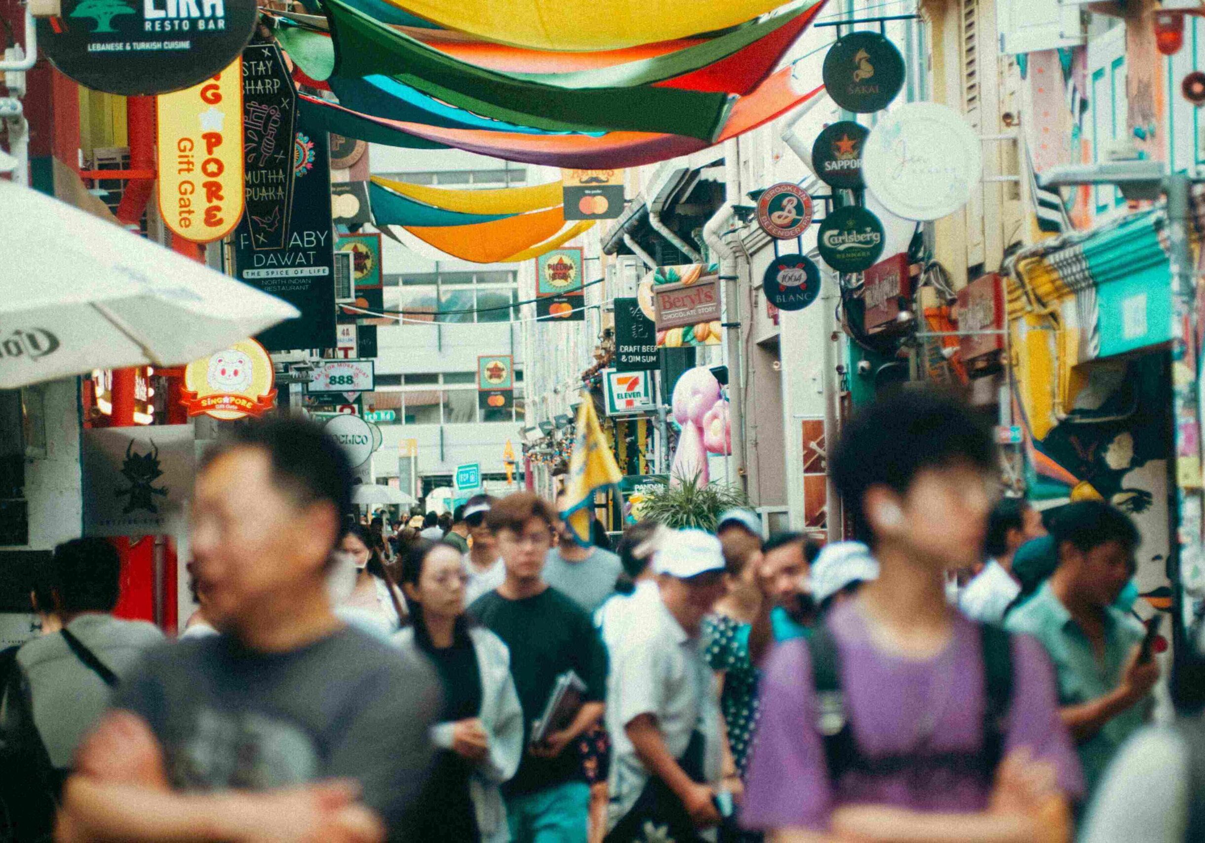 A bustling, vibrant street scene in Singapore, showcasing a variety of hawker and casual dining establishments beneath colorful overhead banners, embodying the city's lively food culture.